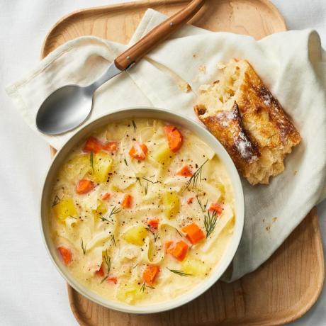 Zdjelica kremaste juhe od kupusa i krumpira pored žlice i komadića tostiranog kruha